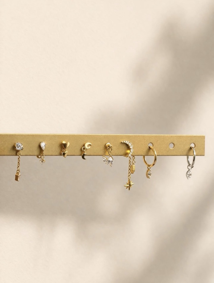 Pendants dorés sur une barre : chaînettes, lunes, étoiles, cœurs et petites breloques