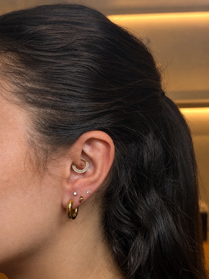 Composition réalisée à l’Atelier Nova : anneau perlé au daith, créole dorée et puces délicates aux lobes