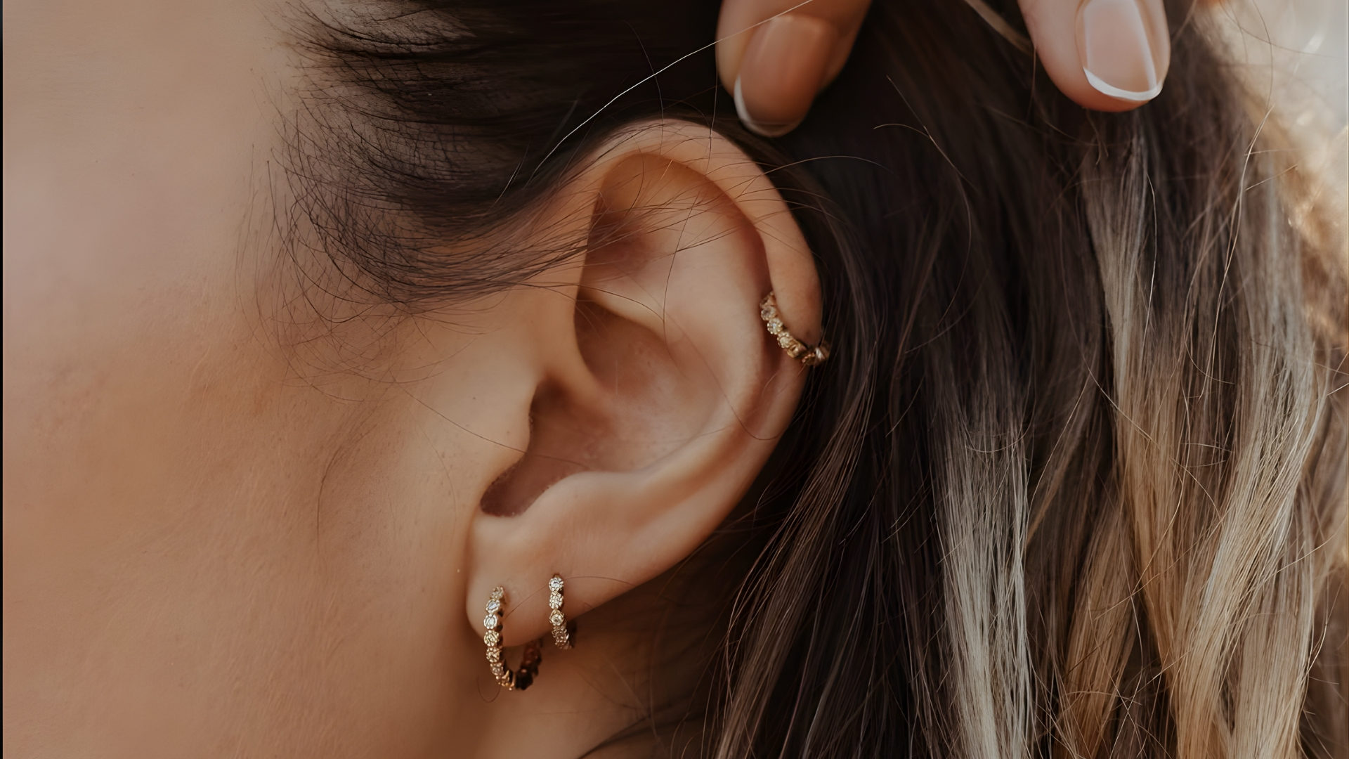 Oreille ornée d’anneaux en or : piercing hélix et double lobe